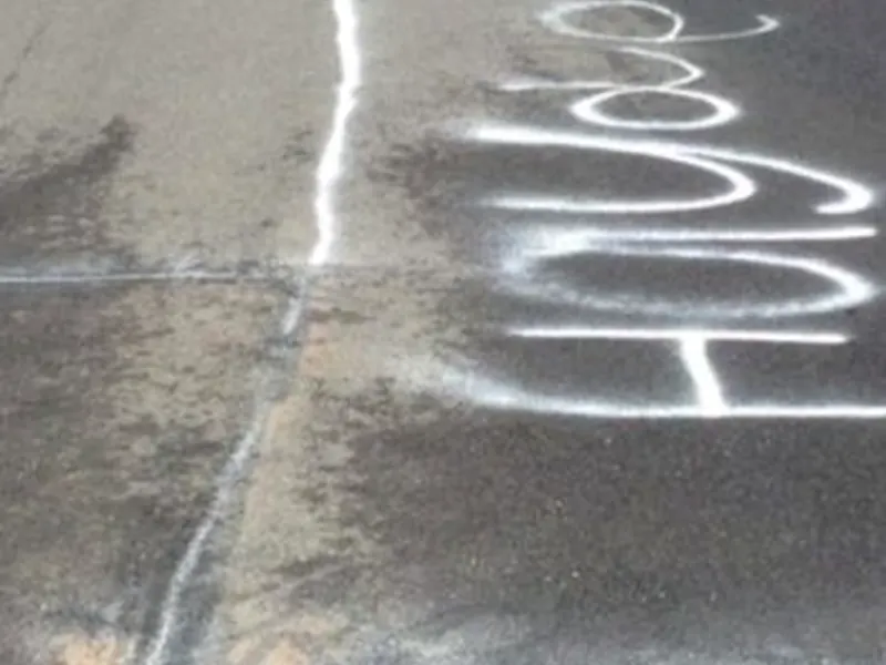 Graffiti removal in progress on pavement