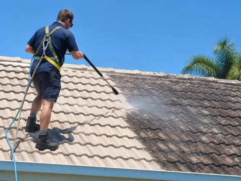 Soft washing being applied to a tiled roof to remove moss and lichen